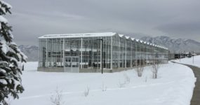 A side view of the Venlo Greenhouse by Prospiant in a snowy field with mountain sighted at the background