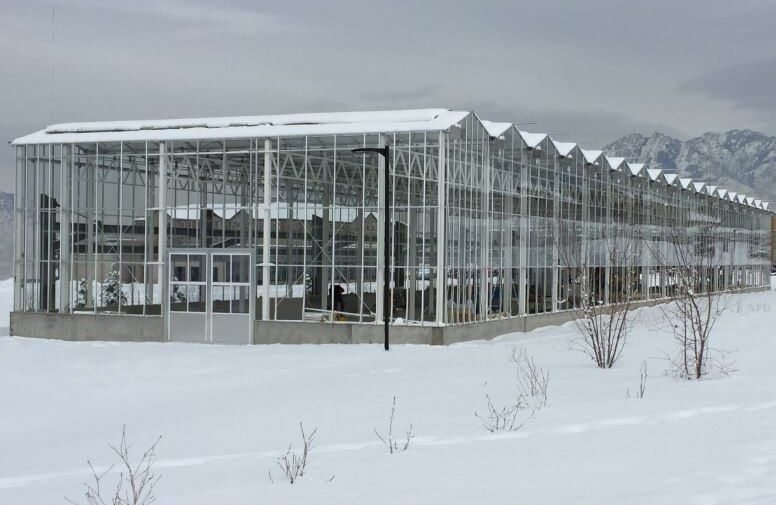 A side view of the Venlo Greenhouse by Prospiant in a snowy field with mountain sighted at the background
